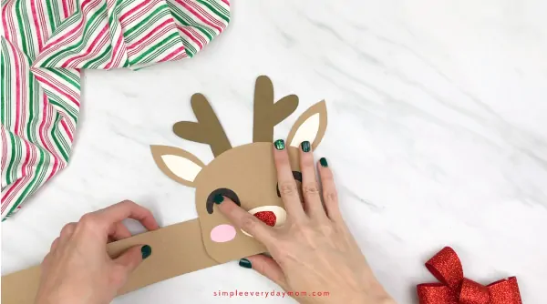 hands gluing headband straps to reindeer