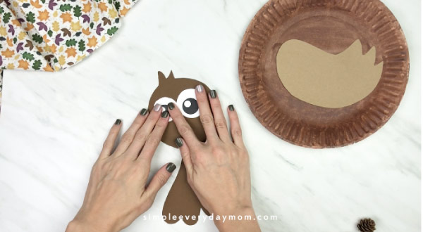 hands gluing eyes onto paper plate turkey craft