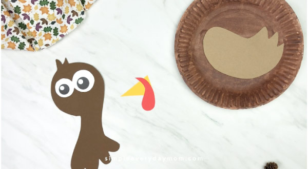 hands gluing beak onto paper plate turkey craft