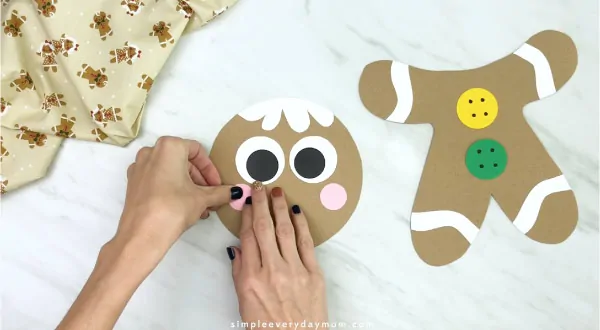 hand gluing cheeks to paper bag gingerbread craft