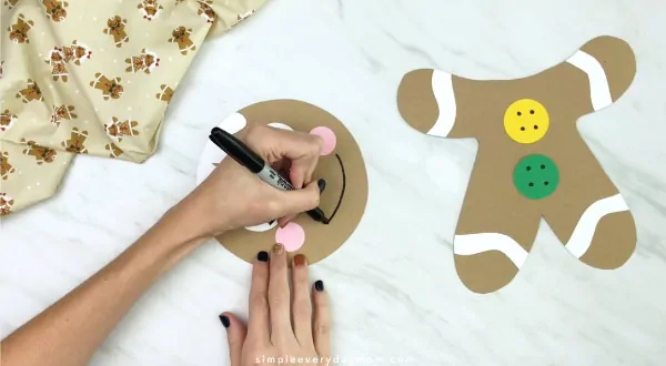 hands drawing a smile on paper bag gingerbread man craft