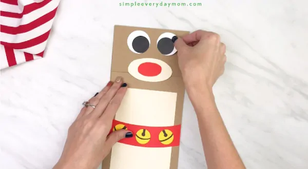hand gluing eyes onto paper bag reindeer craft