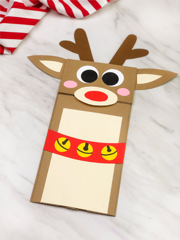 hand gluing antlers onto paper bag reindeer craft