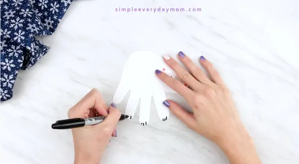 Hands drawing claws onto handprint polar bear 