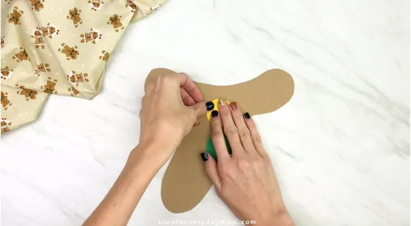 hand gluing buttons to paper bag gingerbread craft