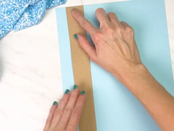hands gluing brown paper onto blue paper