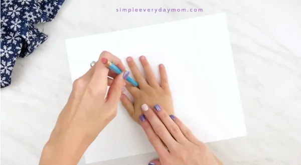 Hands tracing child hand onto white paper 