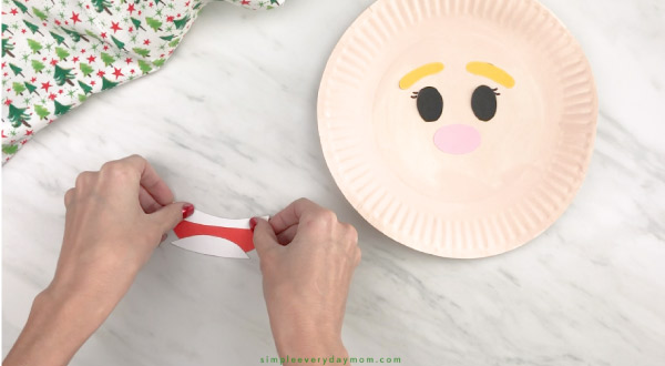 hands gluing mouth together for paper plate elf craft