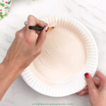 hands painting paper plate peach