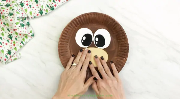 hand gluing muzzle onto paper plate reindeer craft 