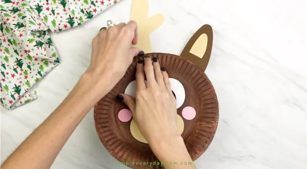 hand gluing antlers onto paper plate reindeer craft