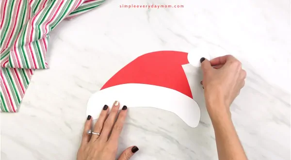 hand gluing pom to end of paper santa craft