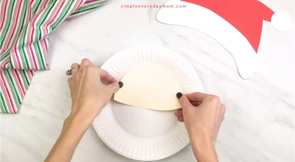hands gluing face to paper plate Santa craft
