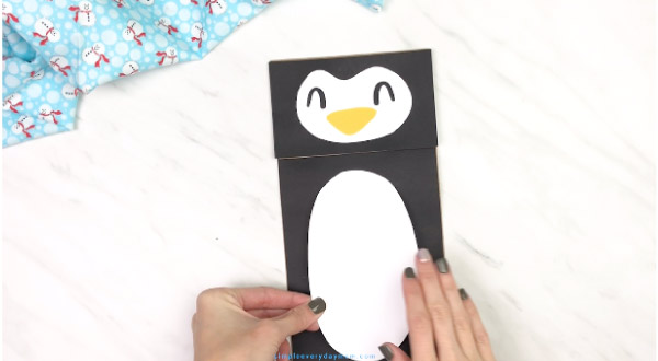 hands gluing belly onto paper bag penguin craft