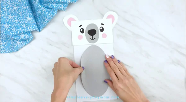 Hands gluing belly to paper bag polar bear craft 