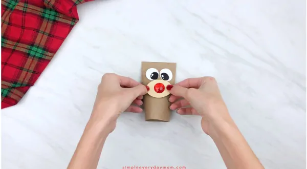 hands gluing nose onto toilet paper roll reindeer craft