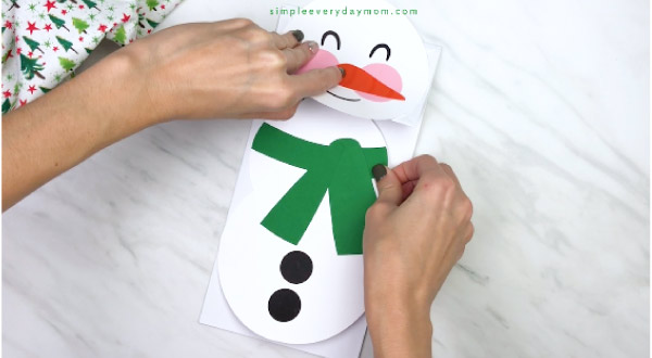 Hands gluing body on paper bag snowman craft