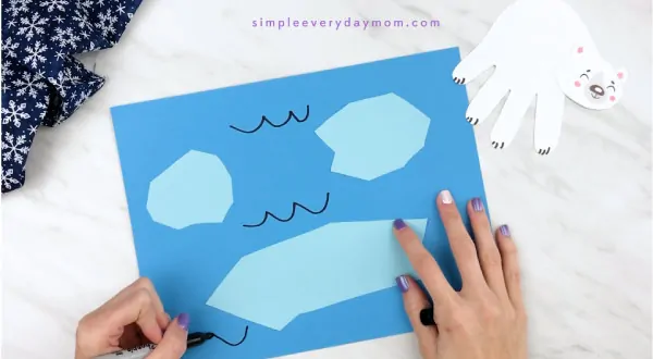Hands drawing water marks onto blue paper 