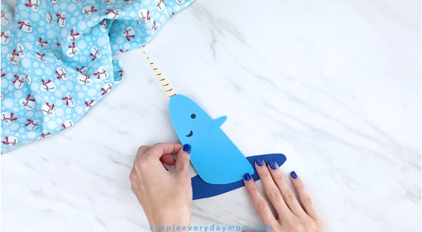 Hands gluing narwhal craft to water 