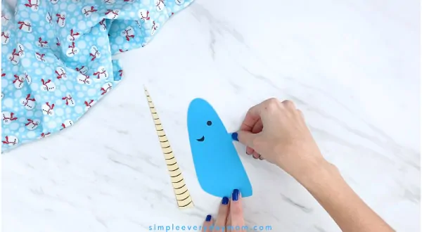 Hands gluing narwhal fin to narwhal craft 