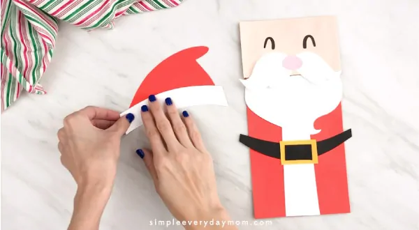 Hands gluing Santa hat together 
