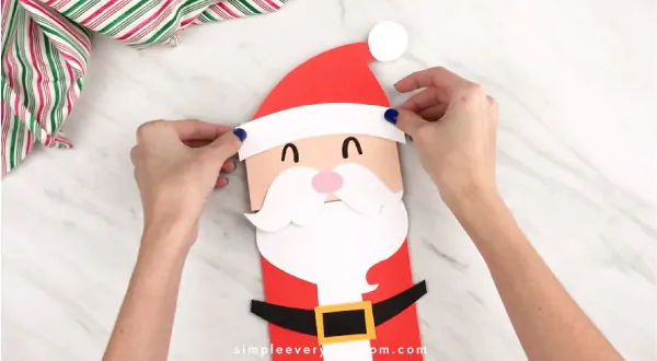 Hands gluing Santa hat to paper bag Santa craft 