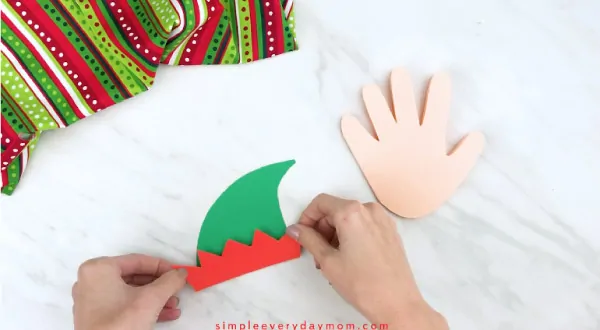Hands gluing elf hat bottom on hat base 