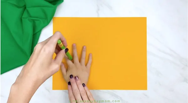 Adult hand trace child hand onto yellow paper 