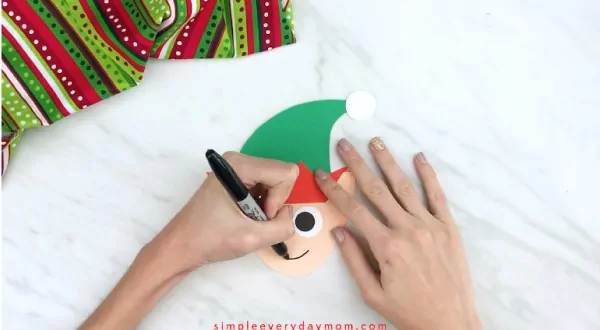 Hands drawing smile on handprint elf 