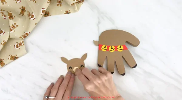 Hands gluing muzzle onto handprint reindeer face 