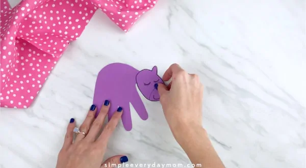 Hands gluing unicorn head to handprint body 