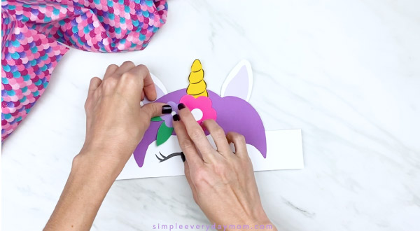 Hands gluing flowers to unicorn headband 