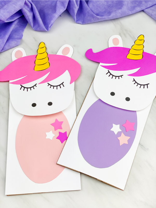 two unicorn paper bag puppets with purple fabric 