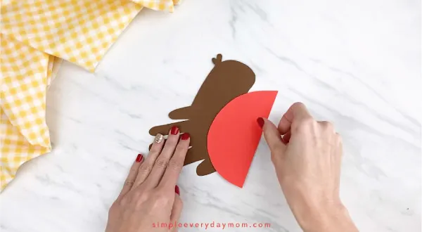 hands gluing red paper to handprint robin craft