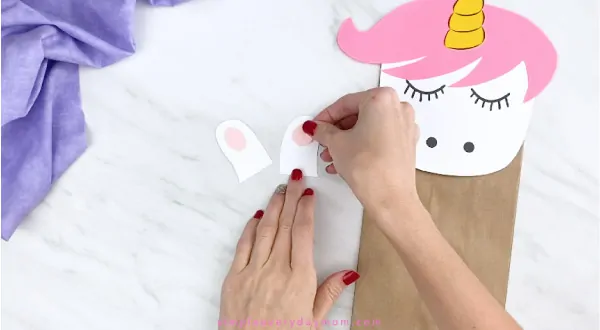 hands gluing inner ears to paper unicorn craft