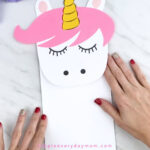 hands gluing body onto unicorn paper bag puppet