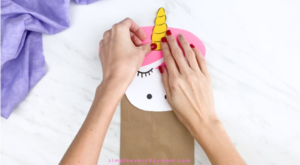 hands gluing unicorn horn onto paper bag unicorn 