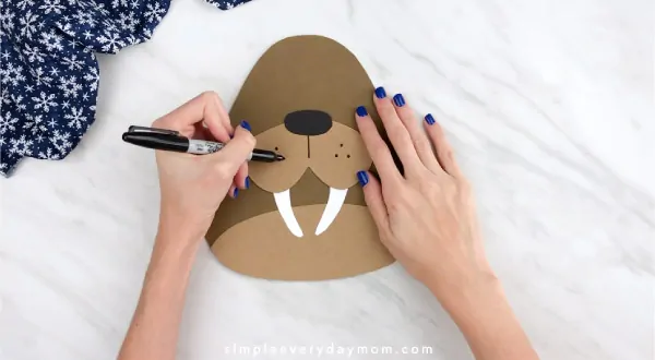 Hands drawing walrus whisker holes on craft 
