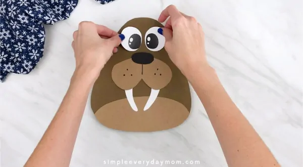 Hands gluing eyes to walrus craft 
