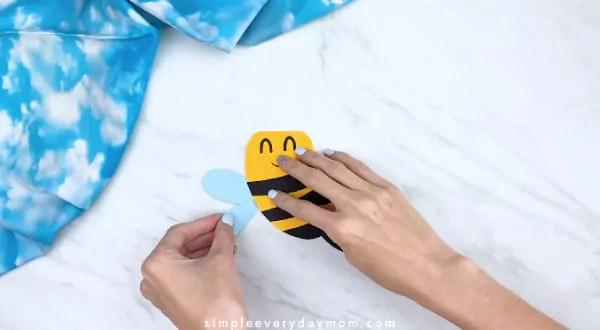 Hands gluing wings to back of bee card craft 