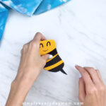 Hands gluing stinger to paper bee card