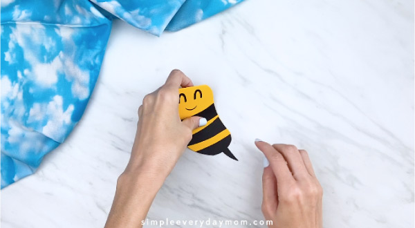 Hands gluing stinger to paper bee card 