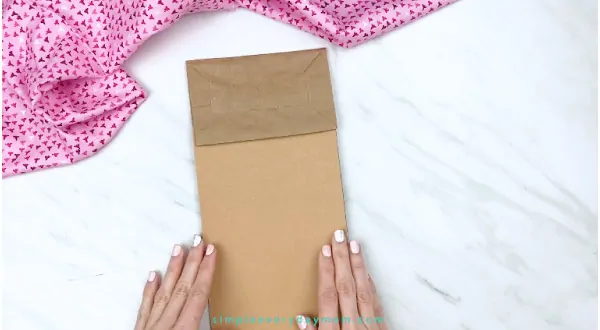 hands gluing brown paper on to paper bag 