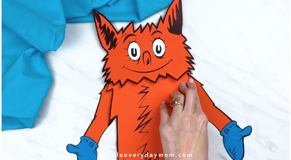 Hands gluing fox arms to paper bag craft 