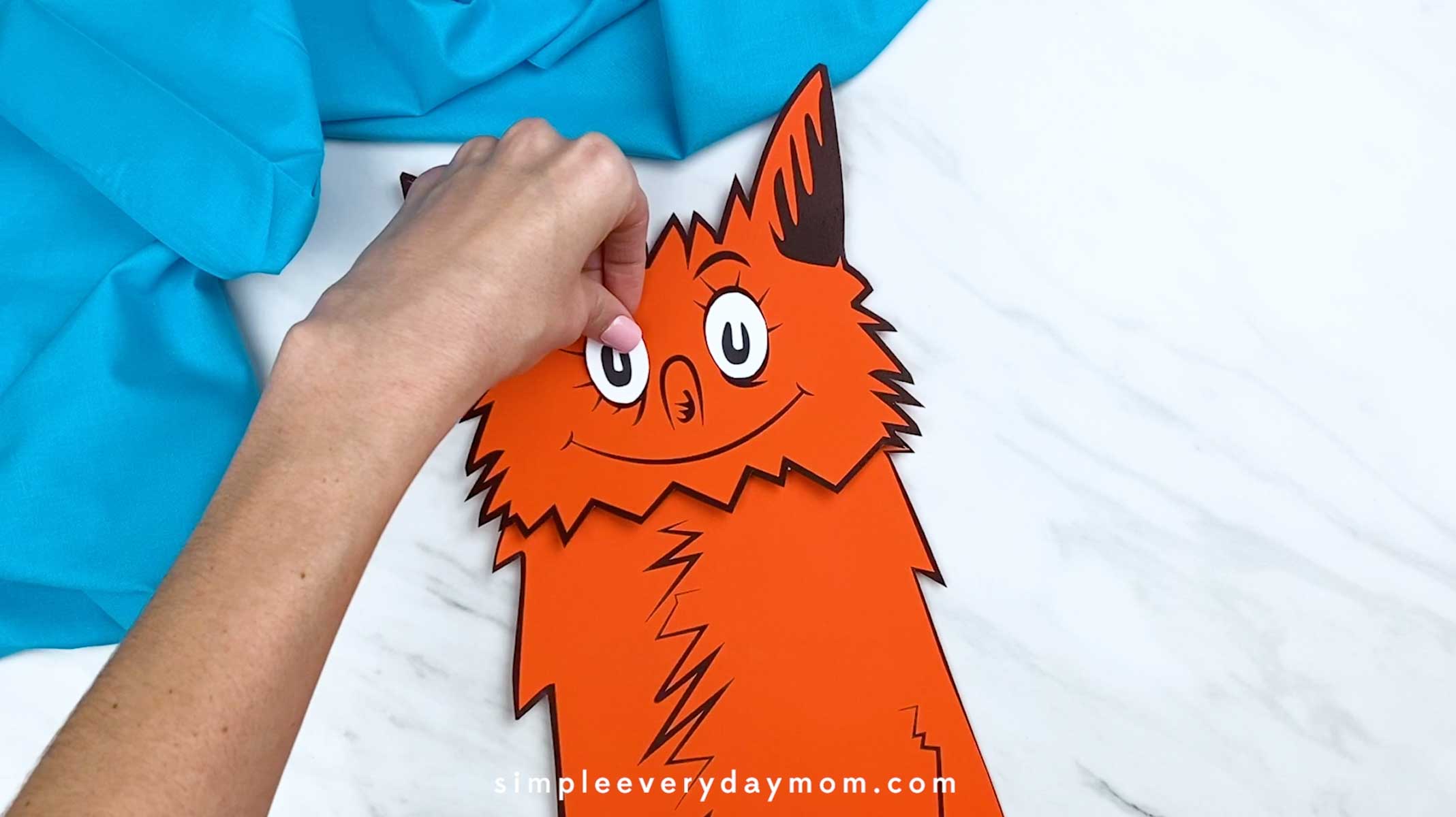 Hand pressing down on the fox eye to secure it to the head.