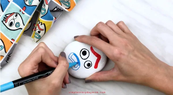 hands coloring in Forky\'s mouth with blue paint pen 