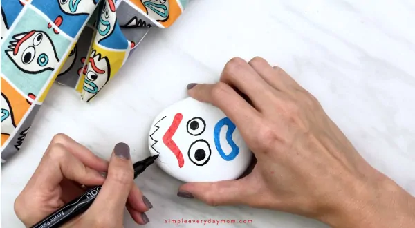 hands drawing on forky prong onto Forky painted rock 