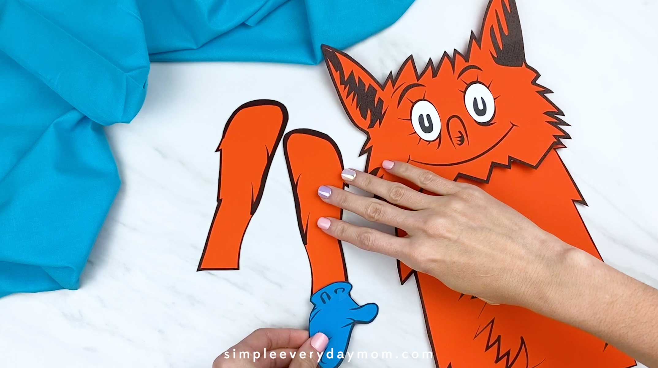 Hands attaching a blue socks to fox's arm