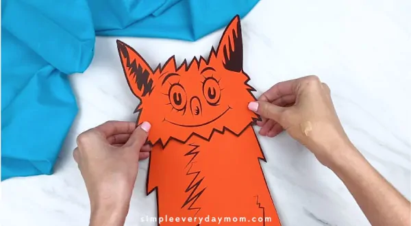 Hands gluing fox in socks head to paper bag 