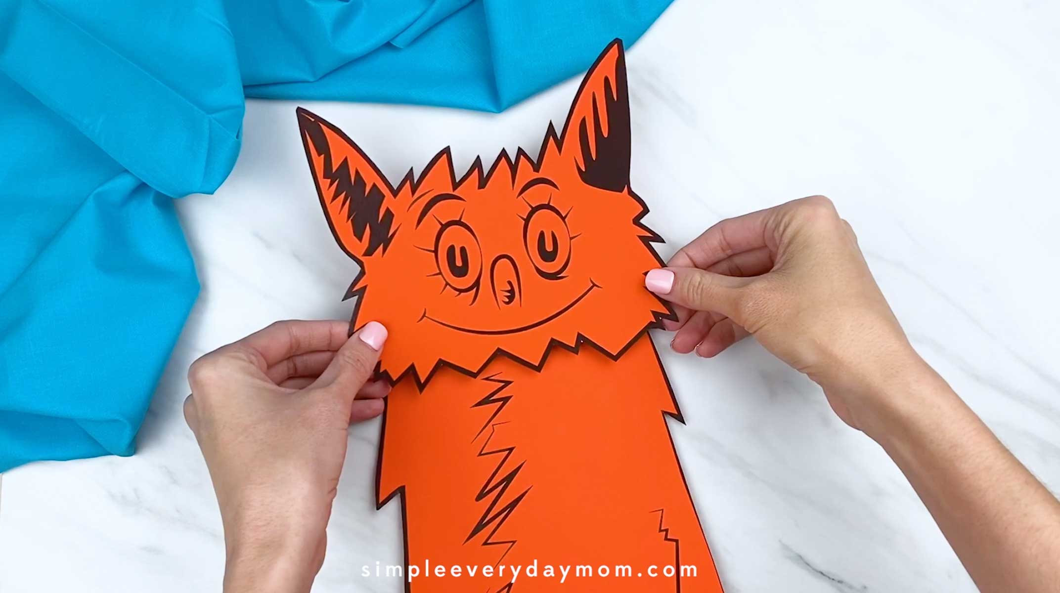 Hands positioning the orange fox head onto the body piece during assembly.